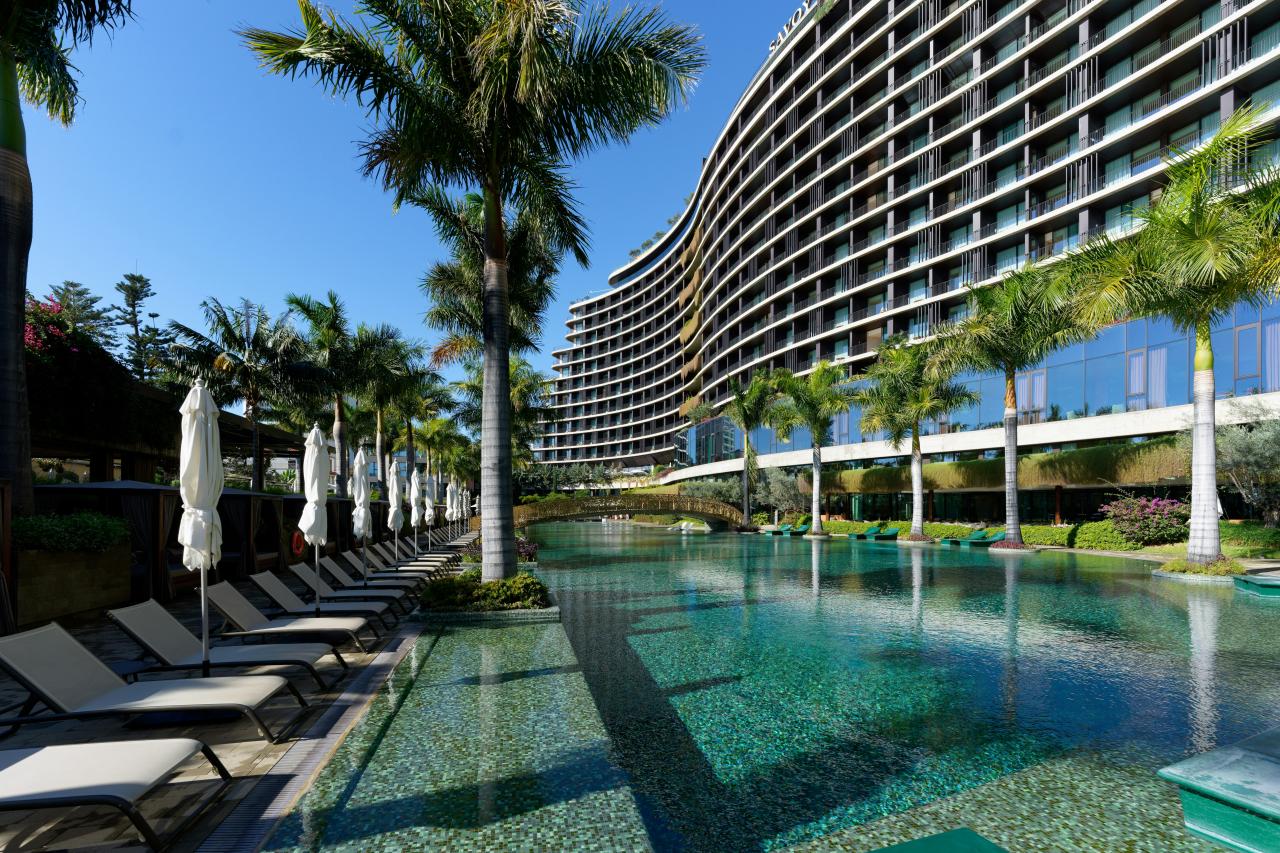 a hotel with a pool and lounge chairs next to it