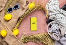 A table with a cell phone, headphones, a scarf, and some other