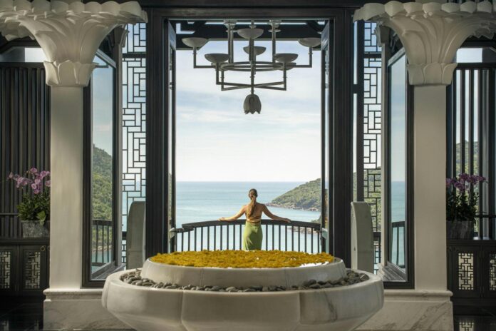 A woman standing in front of a large window with a view of the ocean