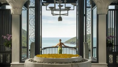 A woman standing in front of a large window with a view of the ocean
